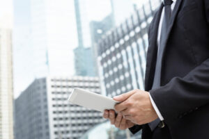 Asesor financiero con traje usando una tablet para gestionar portafolios de inversión en distrito de negocios