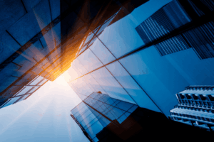 Rascacielos de vidrio azul con reflejo de sol, representando el crecimiento y la solidez en el mercado de inversiones